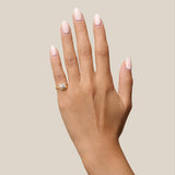 Hand with pink nail polish and a gold ring on a beige background