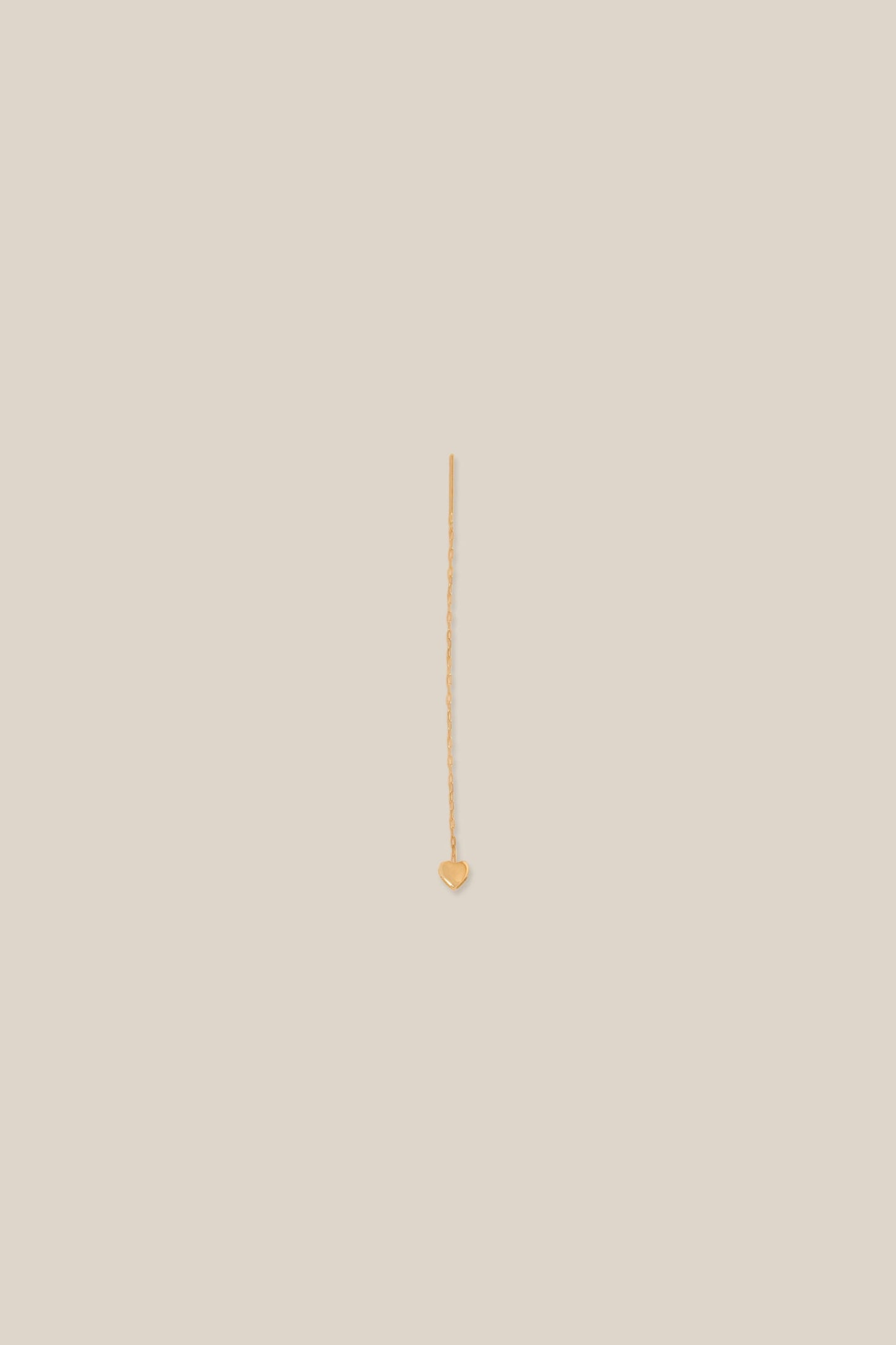 Gold earring on a beige background