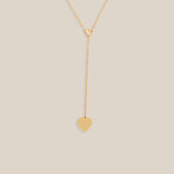 Gold necklace with a heart pendant on a beige background