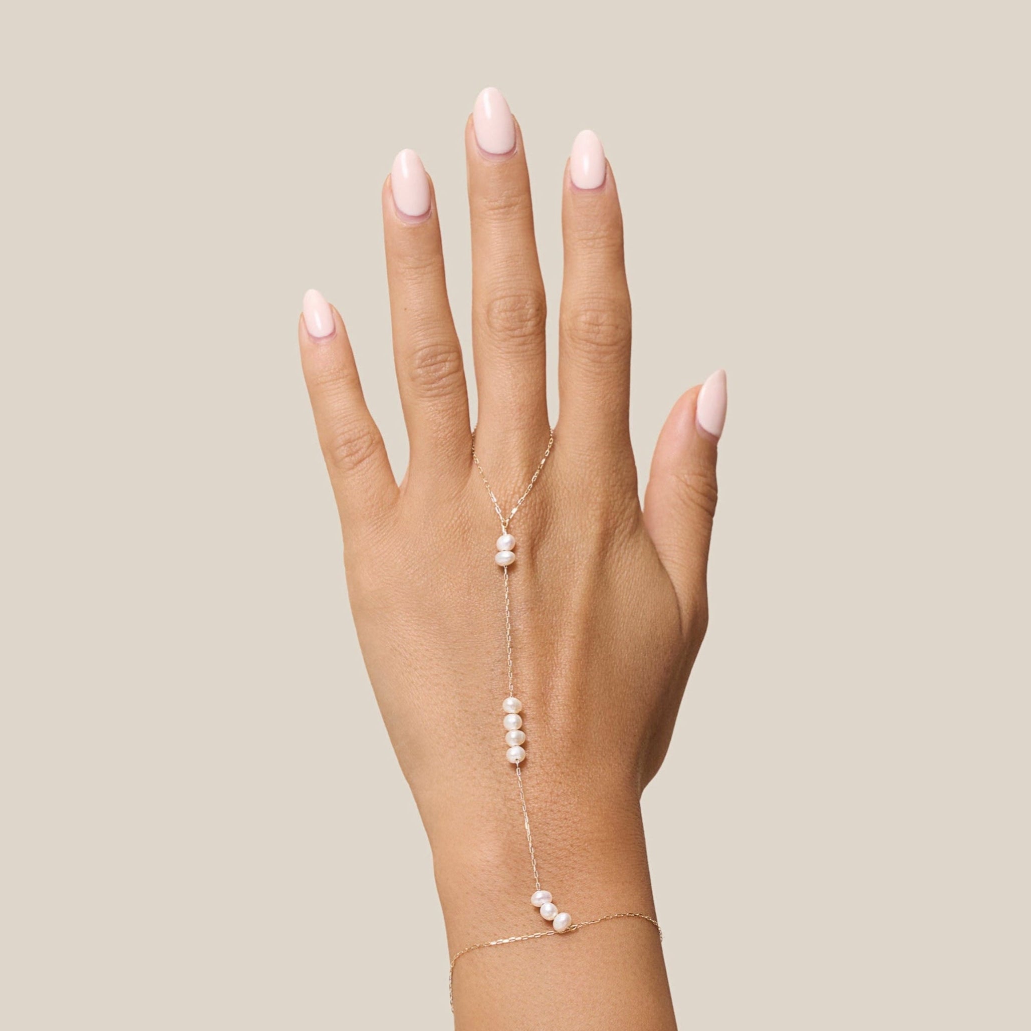 Hand with a delicate bracelet on a beige background