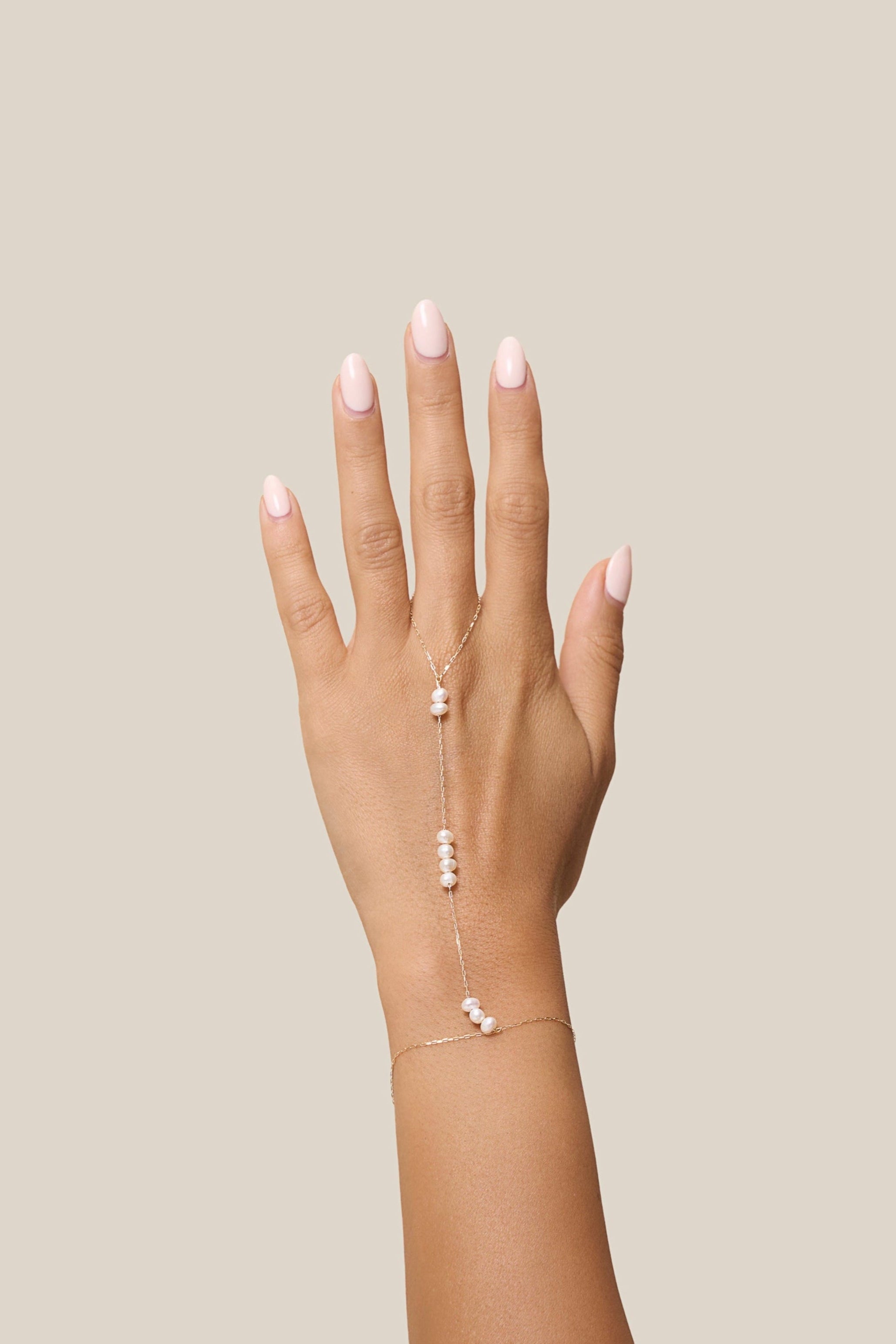 Hand with a delicate bracelet on a beige background