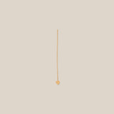 Gold earring on a beige background