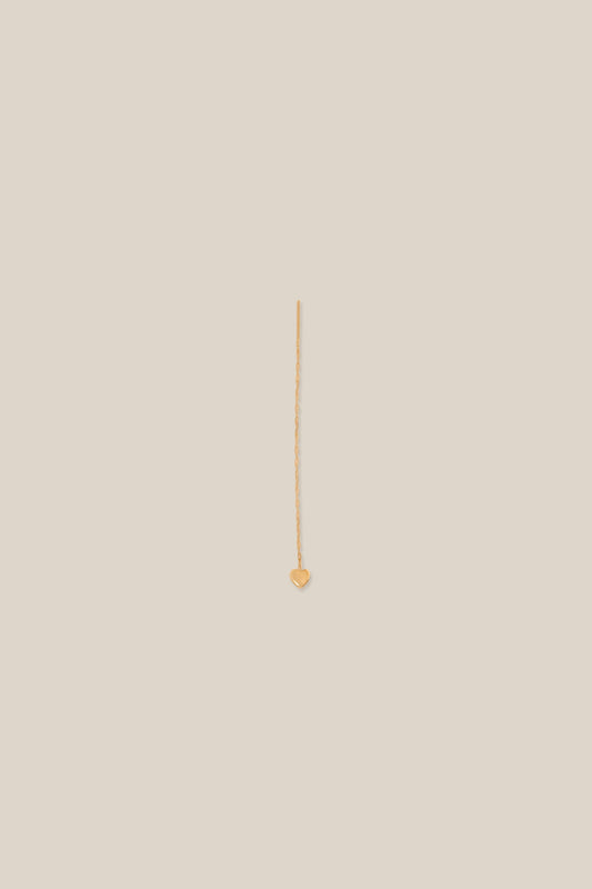 Gold earring on a beige background