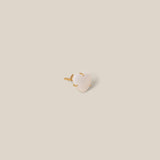 Small white stone with gold base on a beige background
