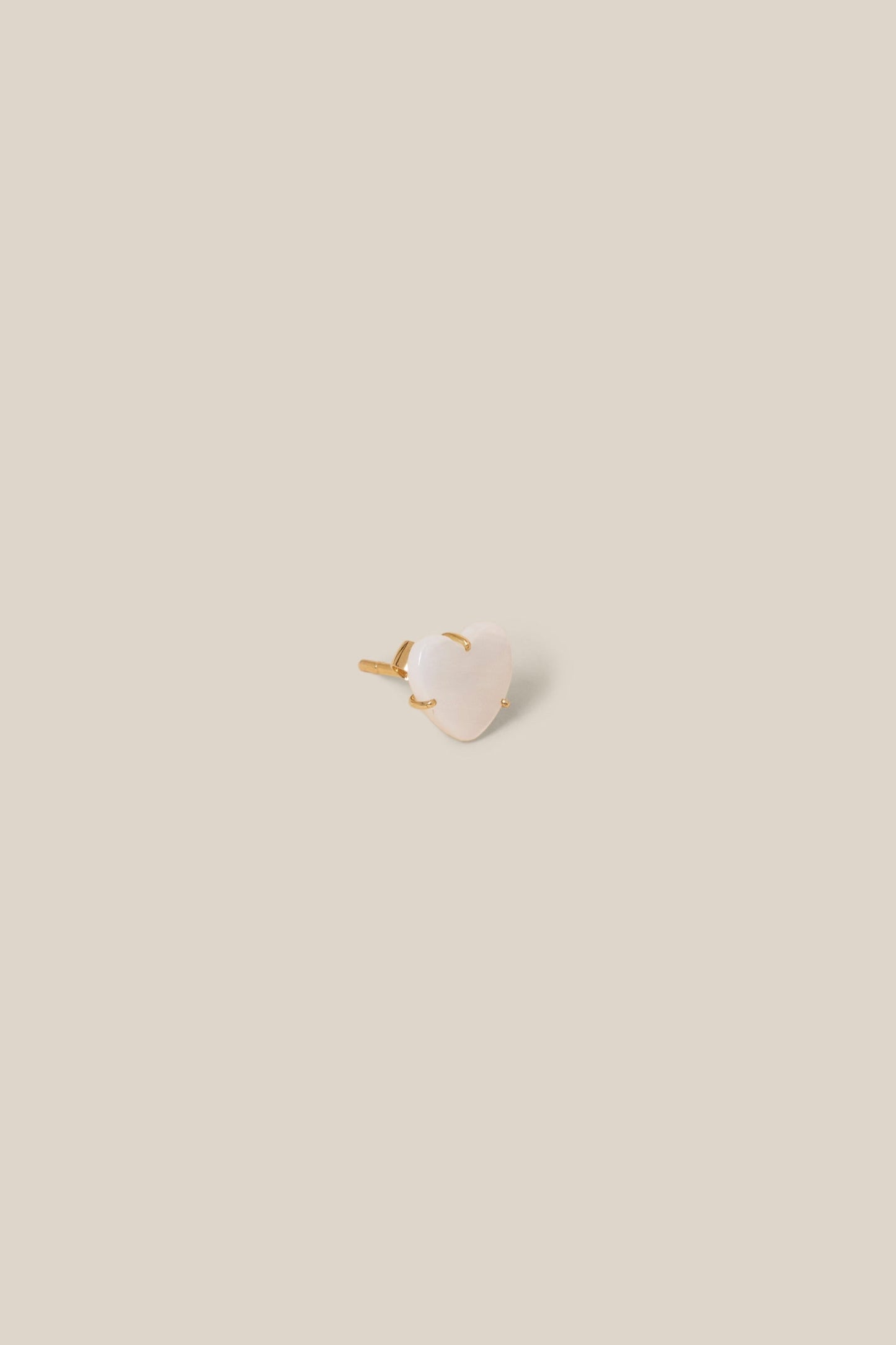 Small white stone with gold base on a beige background