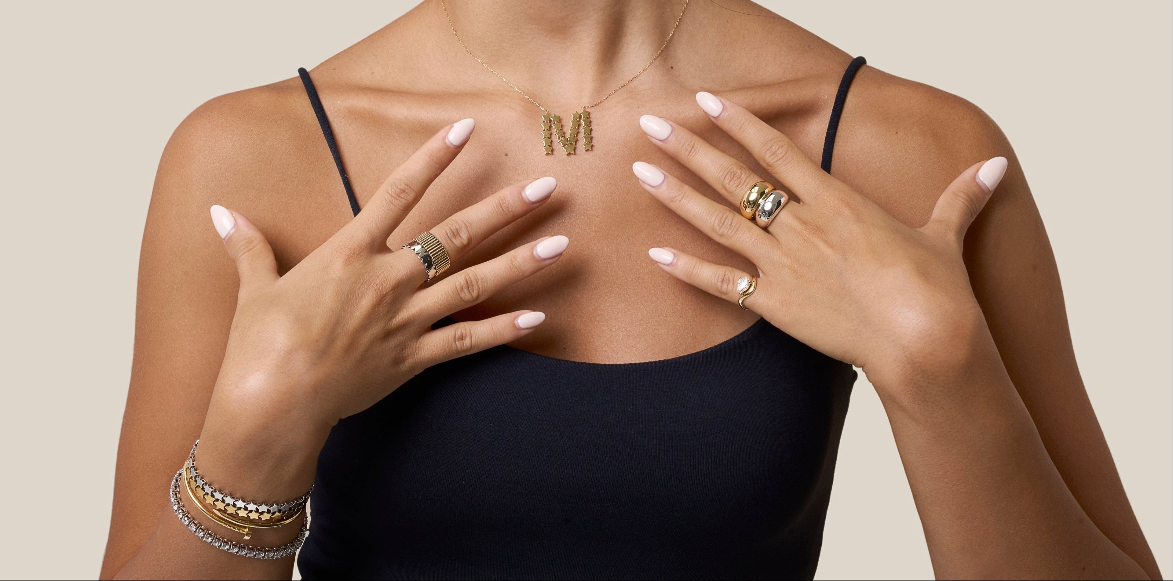 Woman wearing gold jewelry with a neutral background